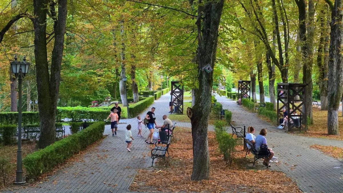 Vizitatori pe o alee umbrită din parcul balnear Băile Govora.