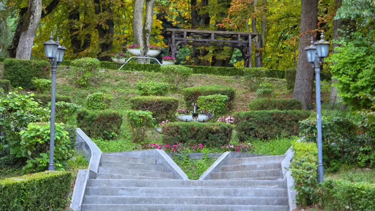 Scări, gard viu și spații verzi amenajate în parcul balnear.
